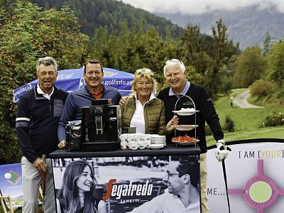 Four smiling people stand by a coffee display outdoors in a scenic mountainous environment, surrounded by greenery and a Segafredo sign.
