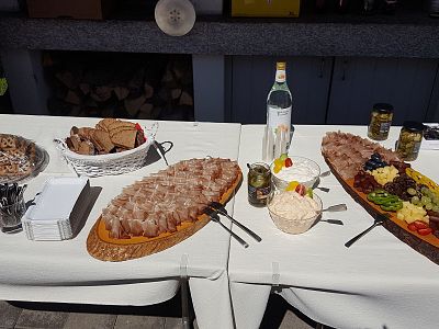 A buffet table with sliced meats on wooden boards, bread baskets, and various condiments, creating a rustic and appetizing presentation.