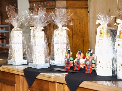 Gift boxes wrapped in clear cellophane with bows on a table, accompanied by colorful nutcracker figures, creating a festive atmosphere.