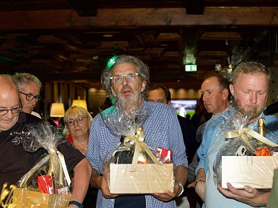 People holding gift baskets at an indoor event, suggesting a celebration or award ceremony.