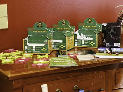 A tabletop with promotional boxes labeled 'Pocket Pro', brochures, and small items against a maroon wall suggests a retail or demonstration setup.