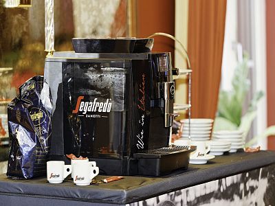 A Segafredo coffee machine with cups and a coffee bag, set up on a table in a room with elegant decor.