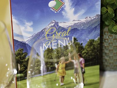 A menu cover showing snow-capped mountains and a golf course with people walking. Title says 'Great Menu' with a logo featuring a golf club.