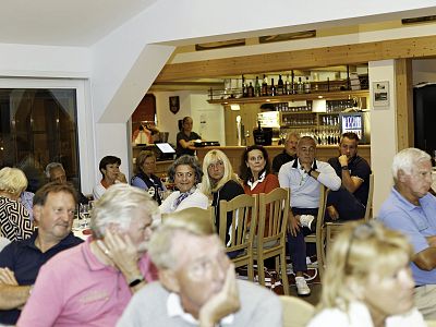 A group of people socializing in a café, sitting around tables and bar stools, creating a lively and friendly atmosphere.