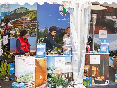 Booth with vibrant images of mountains and resorts, featuring people interacting, promoting travel destinations.