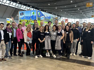 A group of people posing together at an exhibition with colorful banners in a spacious hall.