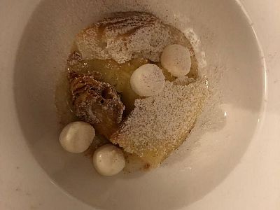 Artistic dessert with apple slices, powdered sugar, and white dollops on a white plate.