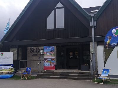 Building entrance decorated with banners, chairs, and promotional displays, suggesting an outdoor event setup, possibly related to hiking or regional activities.
