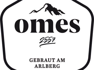 Schwarz-weißes Logo mit einem stilisierten Berggipfel über dem Wort "omes" und der Zahl "2557" darunter. Unten steht "Gebraut am Arlberg".