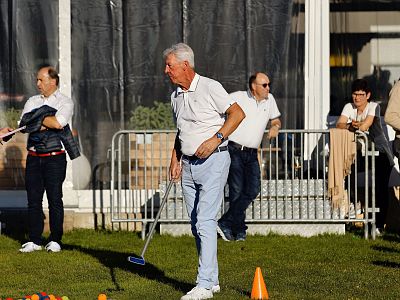 Group of people at an outdoor event on a grassy field, some engaging in games or activities. Cones and various props are scattered around the area.