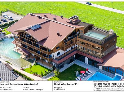 Aerial shot of Wöscherhof Hotel with new modern wing, solar panels, and an outdoor pool in a lush green setting.