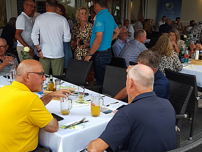 A crowded indoor social event with people sitting and standing, talking and enjoying drinks at a restaurant, with a lively and casual atmosphere.