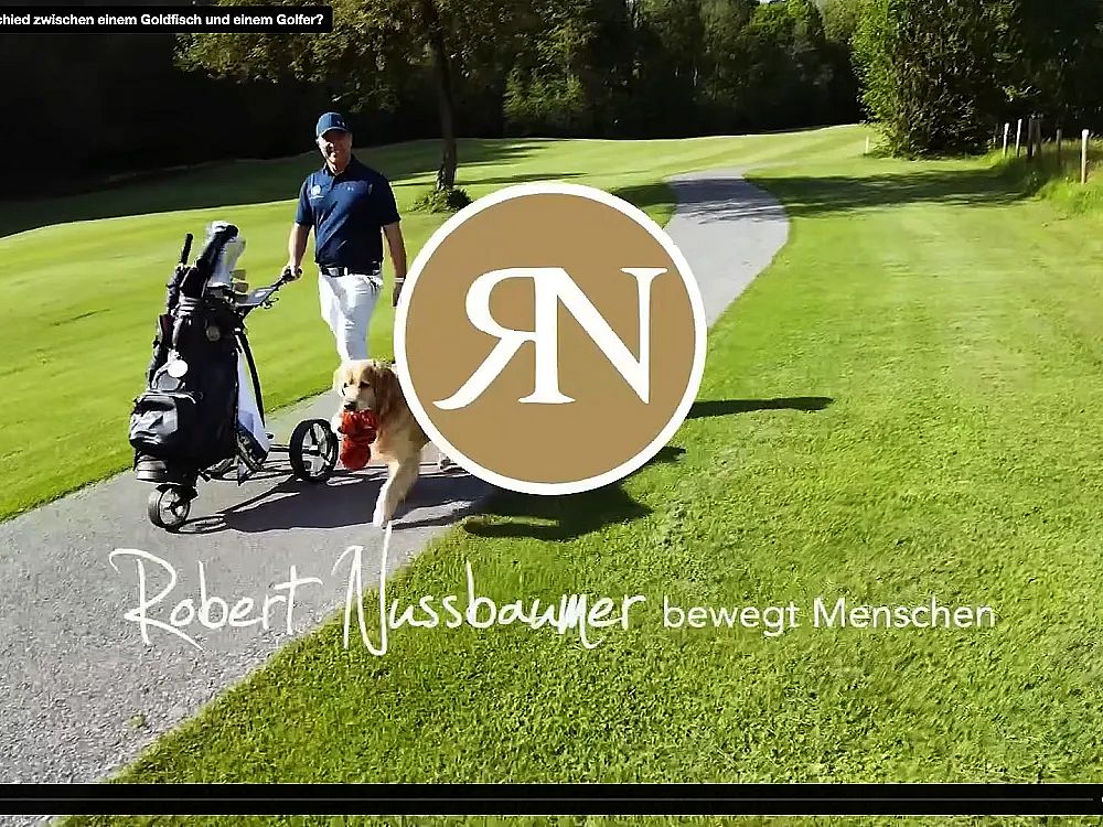 A person with a golf cart and a dog on a golf course, surrounded by greenery and trees.