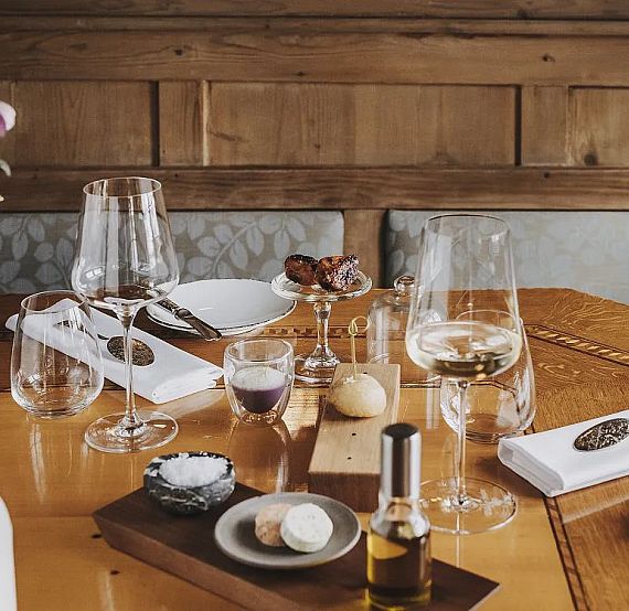 A dining table with elegant glassware, napkins, appetizers, and wooden decor, creating a sophisticated dining atmosphere.