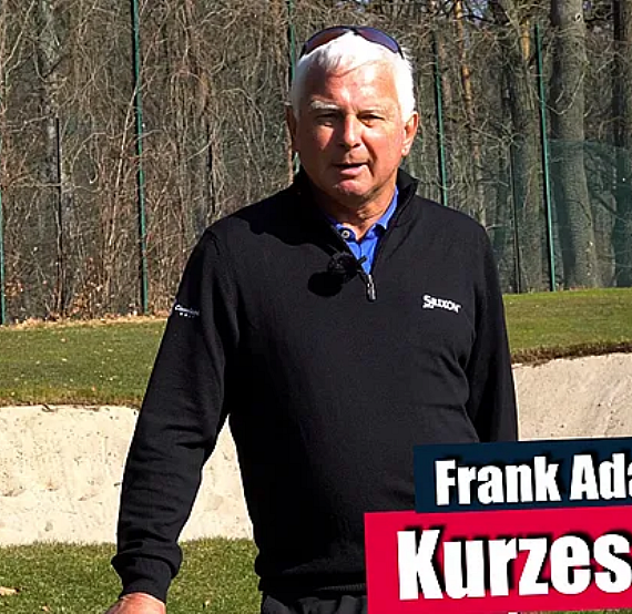 A man stands on a golf course near a sand trap, holding a club. He's dressed in a black sweater and sunglasses, ready to demonstrate golf techniques.