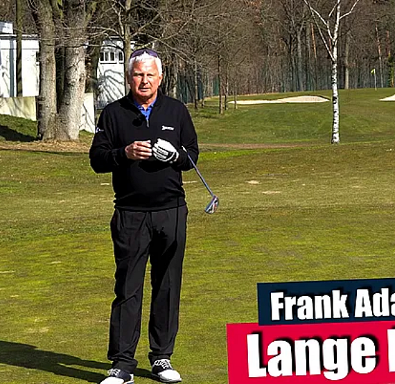 Golfer demonstrates long putt technique on a green with trees and bunkers in the background.