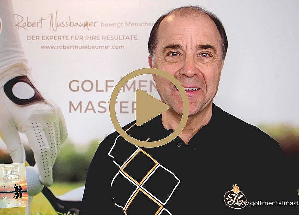 A person in front of a banner about golf mastery, wearing a black shirt with a logo.