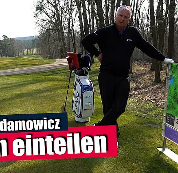A man stands on a golf course next to a golf bag and sign. The text reads: "Frank Adamowicz, Bahn einteilen." Trees and green grass are visible.