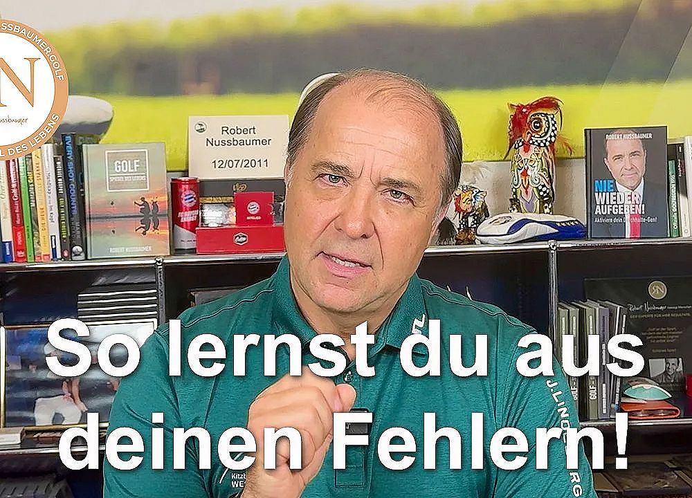 Man in a home office setting, gesturing while speaking, surrounded by books and decorations, with text overlay about learning from mistakes in German.