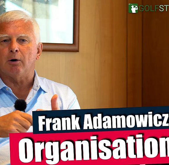 An elderly man speaks into a microphone, wearing a light blue shirt and sitting indoors, as he discusses organization in golf. A logo reading 'GOLFSTUNDE' is visible.