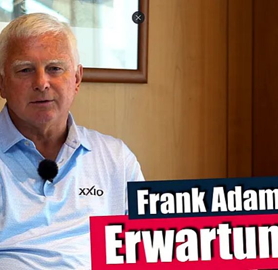 Ein älterer Mann in einem blauen Poloshirt sitzt in einem Raum mit Holzwänden. Neben ihm steht der Text: "Frank Adamowicz Erwartungen".