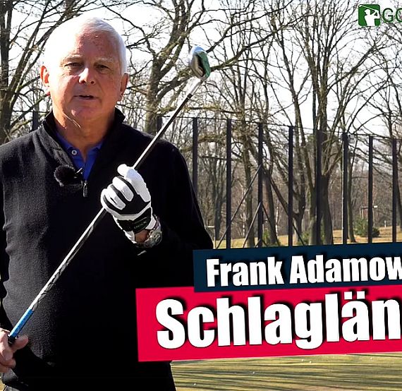 A man holding a golf club on a sunny day in a park or golf course, surrounded by trees.
