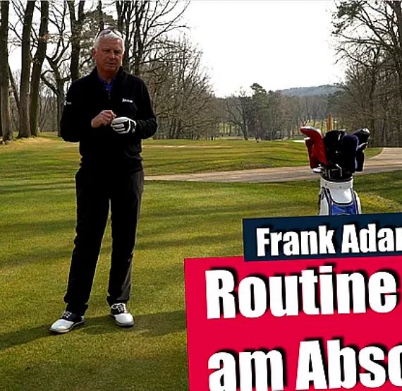 A man stands on a golf course next to a golf bag, demonstrating a routine with trees in the background.