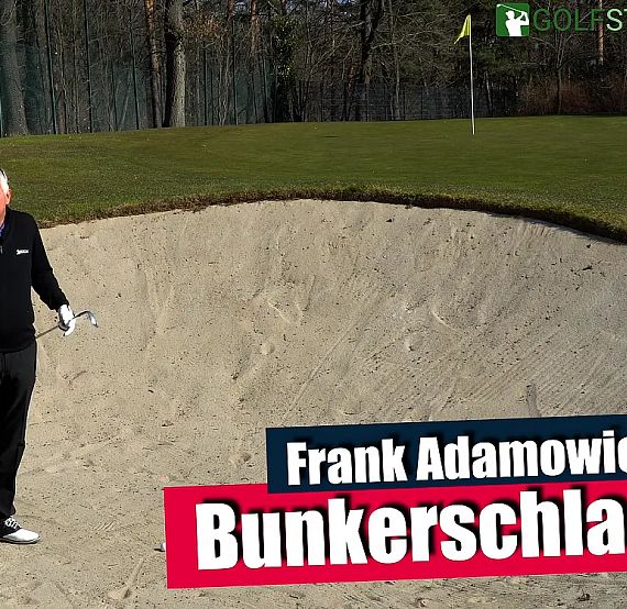 A man stands in a golf bunker holding a club, explaining bunker shot techniques. There's a flagstick in the background on the course.