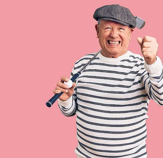 Elderly man in striped shirt and cap holding a paint roller, smiling with enthusiasm against a pink backdrop.