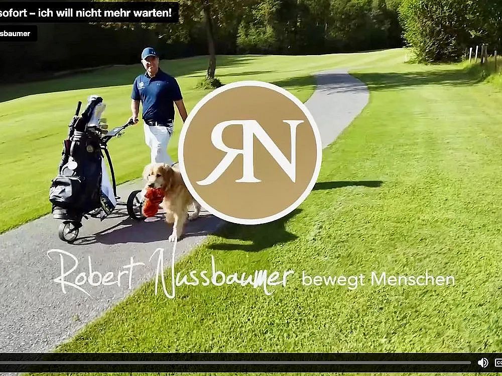A golfer pulling a golf cart along a green path accompanied by a golden retriever. Sunny day, lush greenery, and a sense of leisure and outdoor activity.