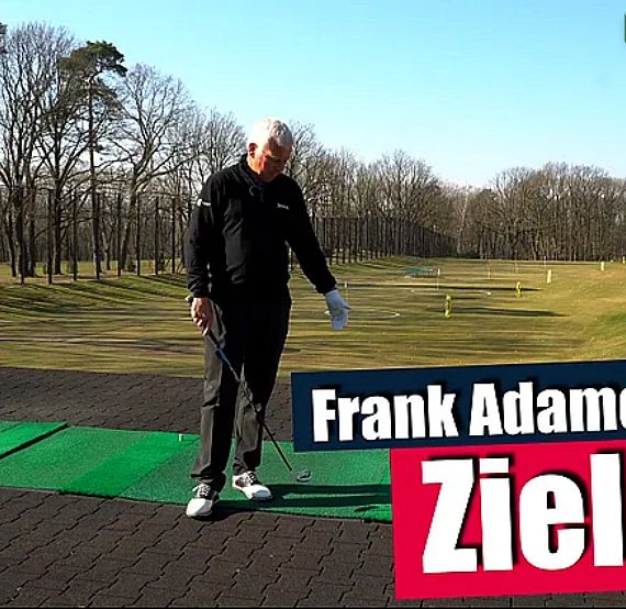 Golf instructor demonstrating aiming on a sunny course with trees in the background.