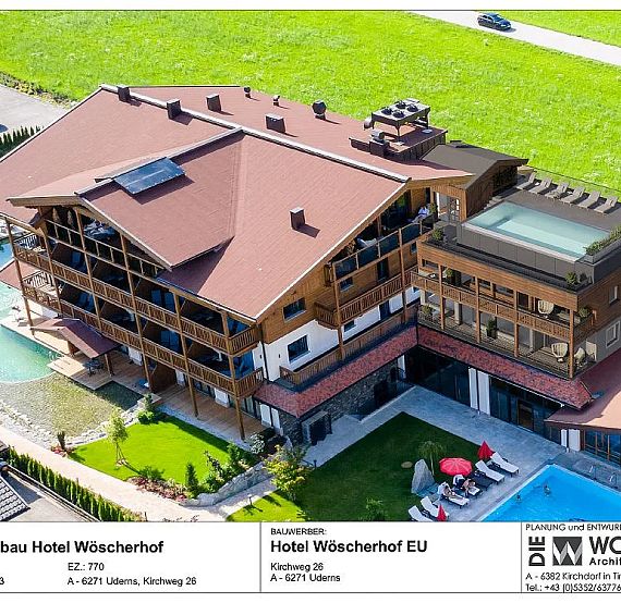 Aerial view of Hotel Wiescherhof with new expansion, featuring a modern design, green surroundings, and a large pool area. Architectural details are visible.