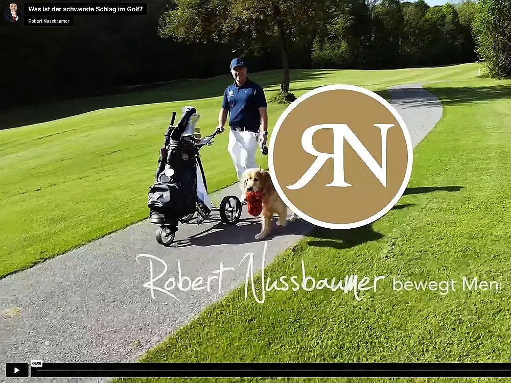 Ein Golfer mit einem Hund geht auf einem Pfad mit einem Golfwagen. Der Hintergrund zeigt einen grünen Golfplatz und der Himmel ist blau.