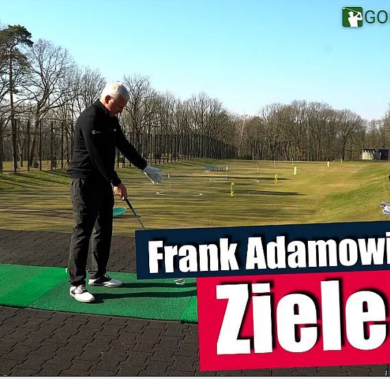 A man holds a golf club on a practice mat outdoors, explaining golf aiming techniques under clear skies.